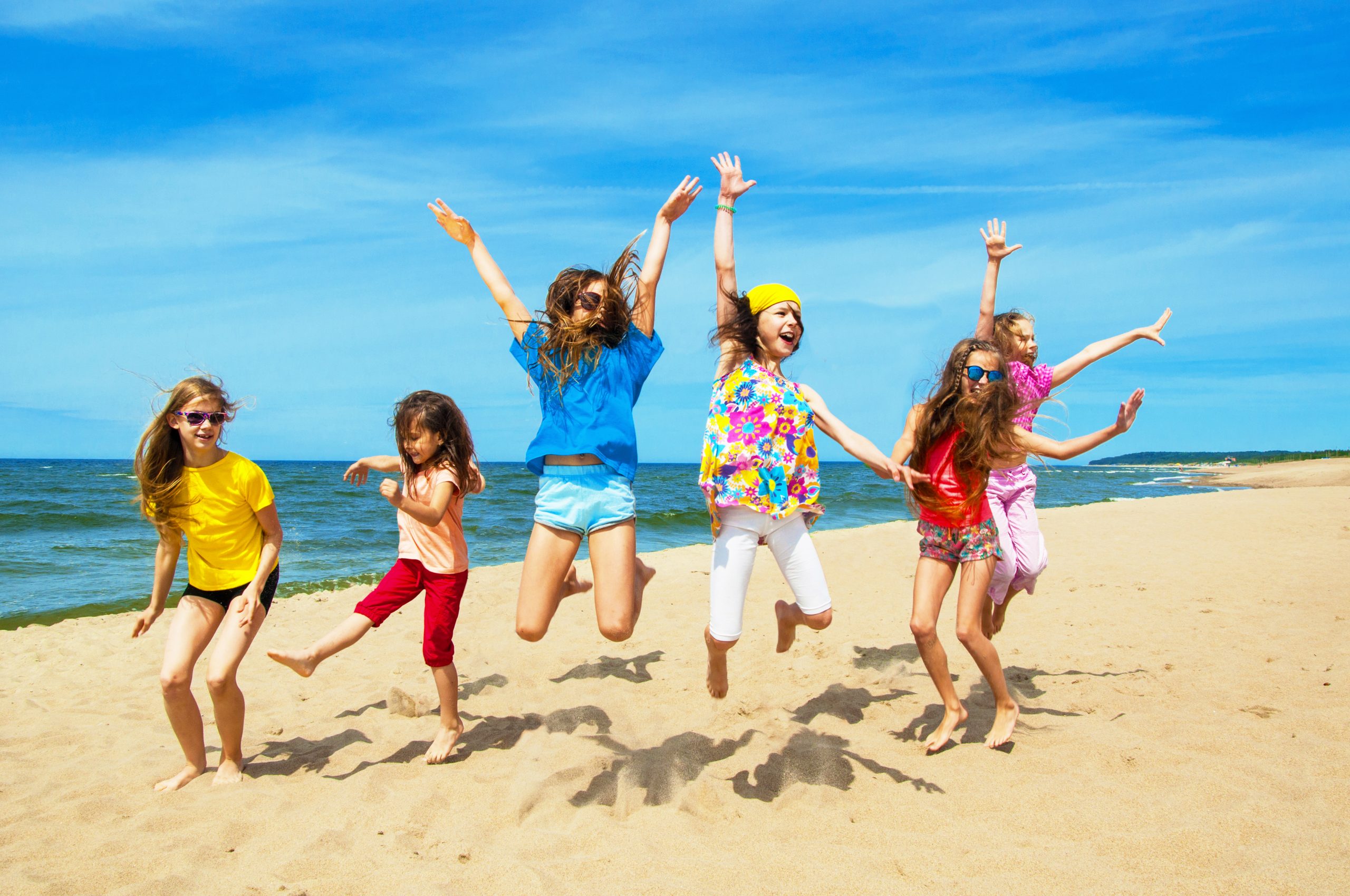A,Group,Of,Children,Jumping,Together,On,The,Beach